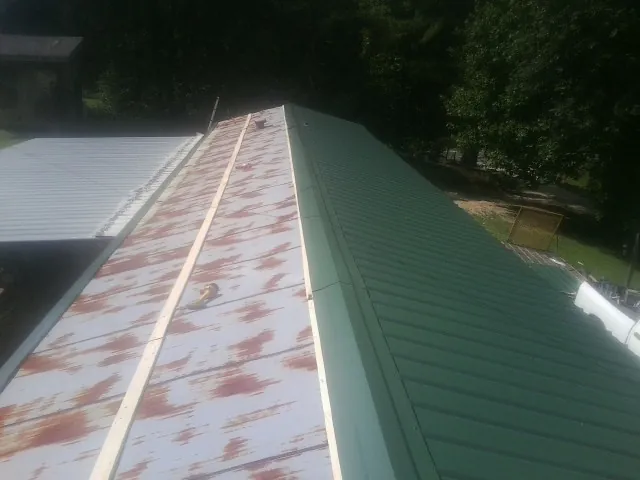 Old rusted panels beside newly installed green metal roofing — Wind Damage Roof Repair by Roofing Brothers in Loganville