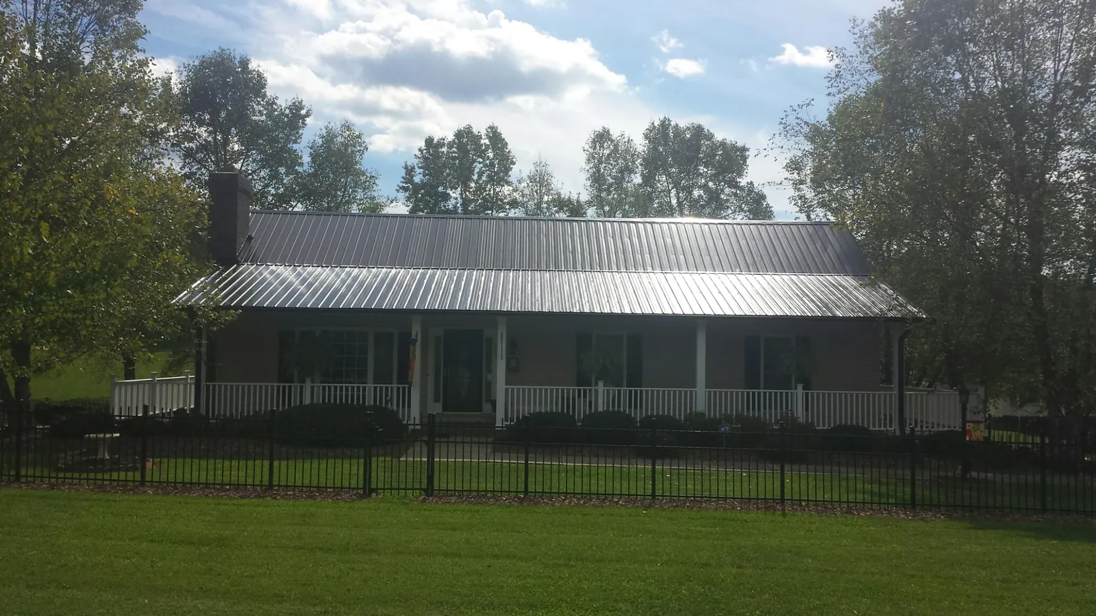 Gray metal roof on a brick ranch with a full width front porch — Gutter Guard Installation work by our crew in Loganville