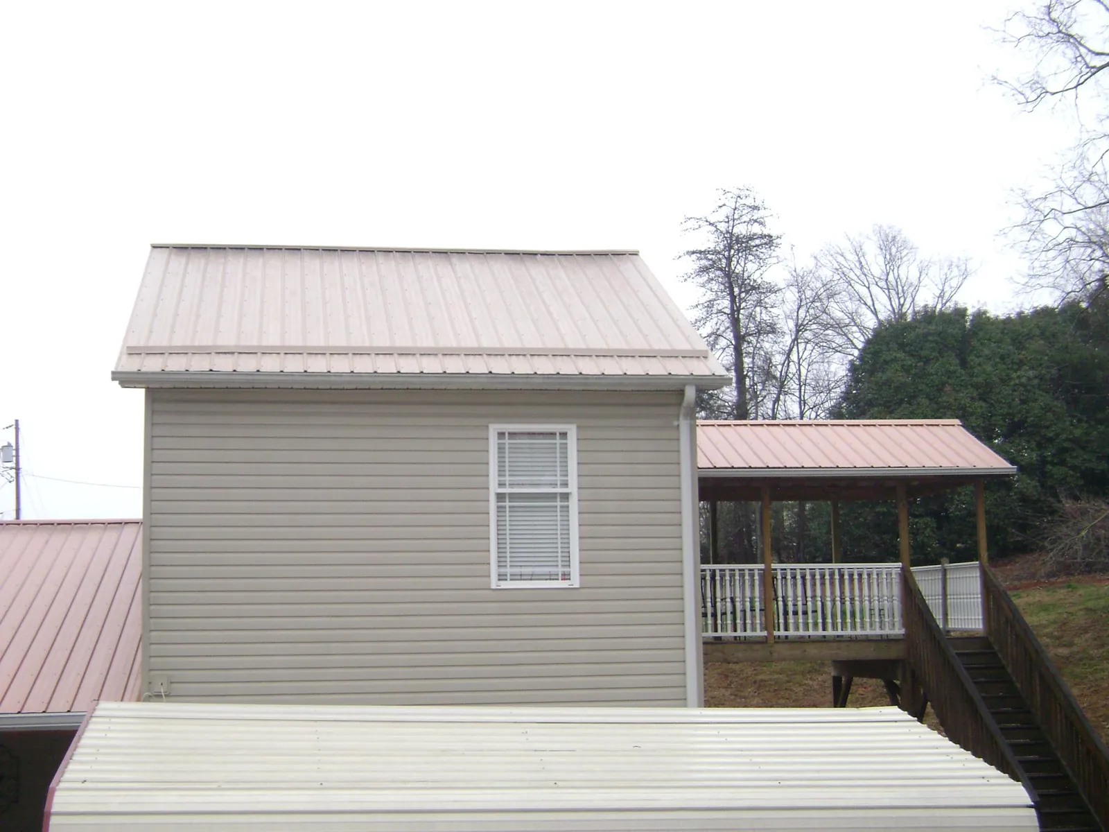 Tan metal roofs on a two story addition and attached porch, from a Roof Replacement job in Loganville